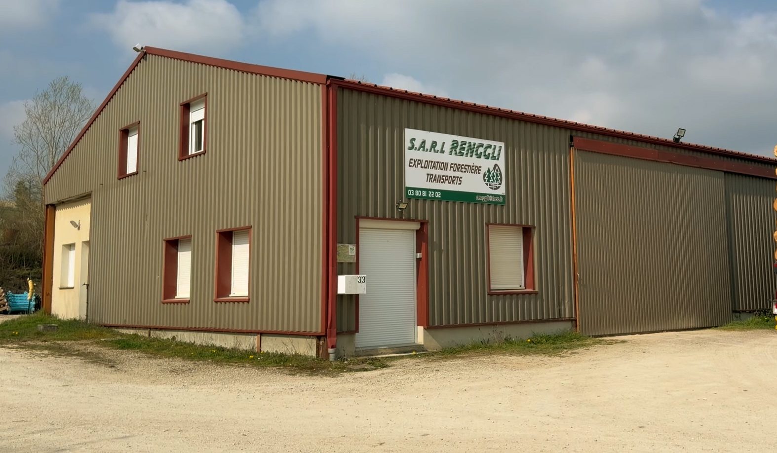 Remorque chargée de grumes devant l’atelier de Montigny-sur-Aube, enseigne S.A.R.L Renggli